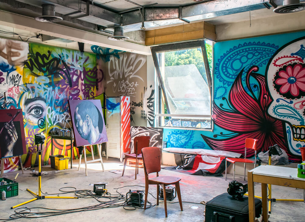 Messy garage space with tall ceilings turned into an art and painting studio